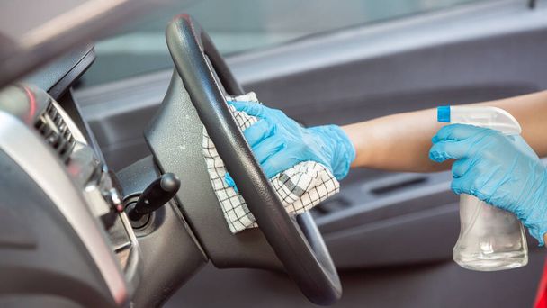 Arabanın içini temizlemek ve dezenfeksiyon sıvısı sıkmak. Eller plastik koruyucu eldivende virüs koronası hastalığından korunmak için vihicle dezenfekte ediyor. - Fotoğraf, Görsel