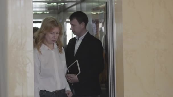 Three business people coming out of elevator in business center. Caucasian businessman and his female coworkers at workplace. Job, lifestyle, confidence, politeness. - Záběry, video