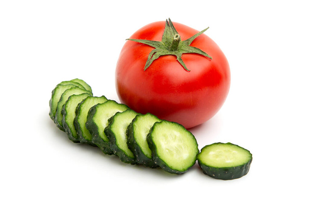 Bright red whole tomato and slices green cucumbers whole isolated on a white background - Foto, Imagen