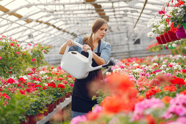 Woman in a black apron working in a greenhouse - Photo, Image