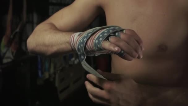 Zeitlupe. Boxer mit nacktem Oberkörper wickelt Bandagen mit amerikanischer Flagge in seine rechte Hand - Filmmaterial, Video