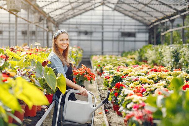 Woman in a black apron working in a greenhouse - Foto, afbeelding