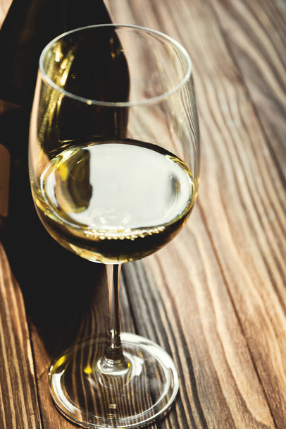glass of white wine and bottle on wooden background, selective focus. - Foto, immagini