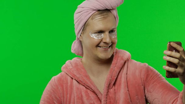 Portrait d'homme transsexuel en peignoir utilisant un téléphone mobile pour un appel vidéo
 - Photo, image