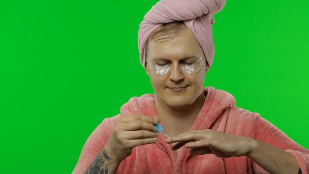 Portret van transseksuele man in badjas die zijn handnagels schildert. Chromatoetsen - Foto, afbeelding