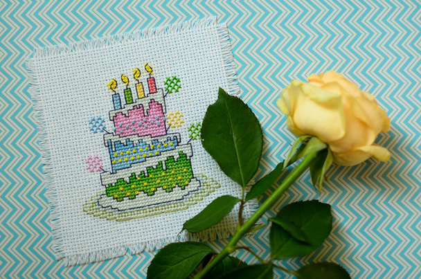 幸せな誕生日の挨拶カード、キャンドルクロスステッチのケーキ、黄色のバラの横にある - 写真・画像