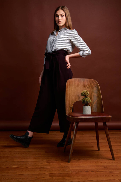 Mininalism style classic studio photo set of the young independent woman. Gorgeous young female in classic suit, black shoes and grey coat. Vintage chair. Woman's clothes. Fashionable clothes. - Photo, Image