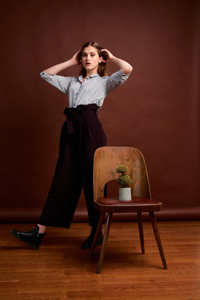 Mininalism style classic studio photo set of the young independent woman. Gorgeous young female in classic suit, black shoes and grey coat. Vintage chair. Woman's clothes. Fashionable clothes. - Foto, immagini