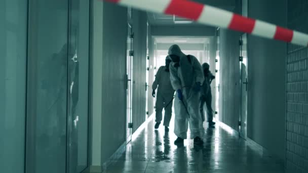 Coronavirus pandémia, vírusmegelőzés, COVID-19 koncepció. Fertőtlenítési szakértők fertőtlenítenek egy folyosót. - Felvétel, videó