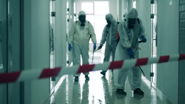 Specialists in splash suits are sanitizing a hallway - Footage, Video