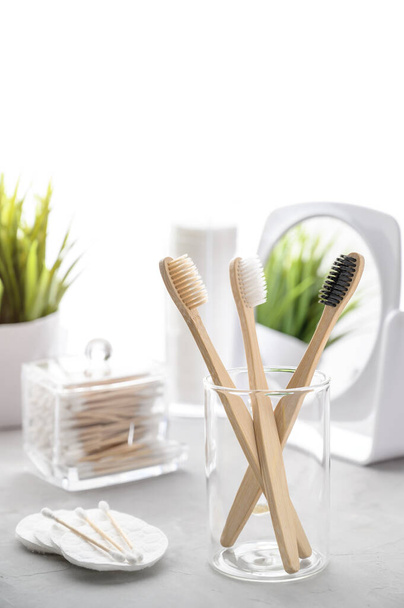 No plastic concept. Eco friendly bathroom accessories. Bamboo toothbrushes, cotton pads and cotton buds on a light gray table. Zero waste. - Foto, Imagen