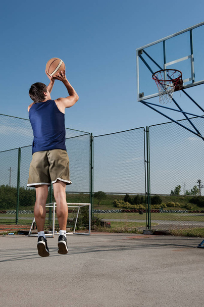 Giovani uomini sportivi che giocano a basket all'aperto in una giornata di sole
 - Foto, immagini