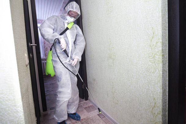 Apartment disinfection. Protection against viruses, insects, mice. In coveralls and respirator - Zdjęcie, obraz
