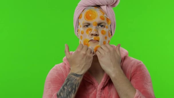 Portret van transseksuele man in badjas kijkend in spiegel met gezichtsmasker - Video