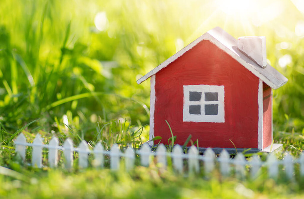 Модель красного деревянного дома на траве - Фото, изображение