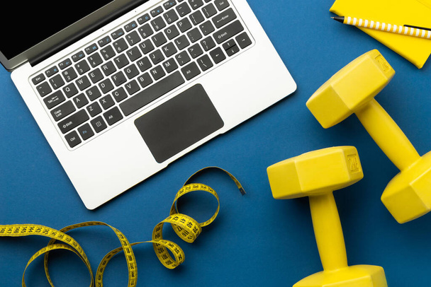 Flat lay vista dall'alto del computer portatile con attrezzature sportive gialle su sfondo blu classico. Stile di vita sano concetto di fitness online
 - Foto, immagini