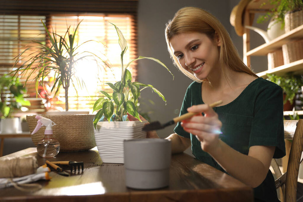 Jovem mulher cuidando de plantas em casa. Passatempo predileto
 - Foto, Imagem