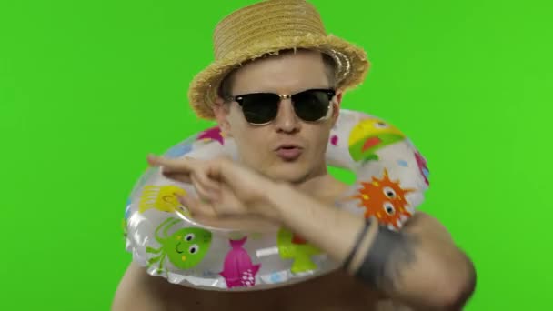 Αδιάβροχος τουρίστας με δαχτυλίδι κολύμβησης, γυαλιά ηλίου. Γιορτάζει, χορεύει. Κλειδί χρωμίου - Πλάνα, βίντεο