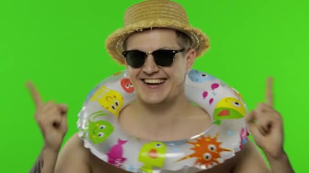 Αδιάβροχος τουρίστας με δαχτυλίδι κολύμβησης, γυαλιά ηλίου. Γιορτάζει, χορεύει. Κλειδί χρωμίου - Πλάνα, βίντεο