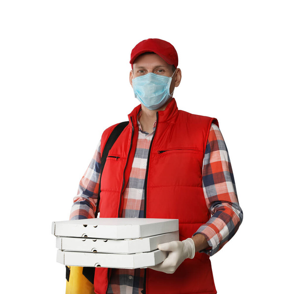 Курьер в защитной маске и перчатках держит коробки пиццы на светлом фоне. Доставка продуктов питания во время карантина коронавируса
 - Фото, изображение