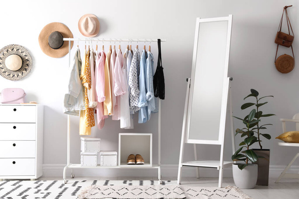 Rack with stylish women's clothes and mirror indoors. Interior design - Photo, image