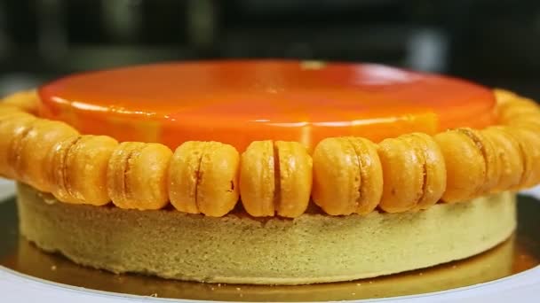 delicious whole round orange glazed cake with mini macaroons rotates around - Footage, Video