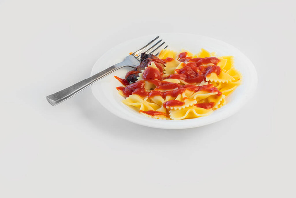 Shot on a white background. No isolation. White plate in it pasta and a piece of meat and a fork - Photo, Image
