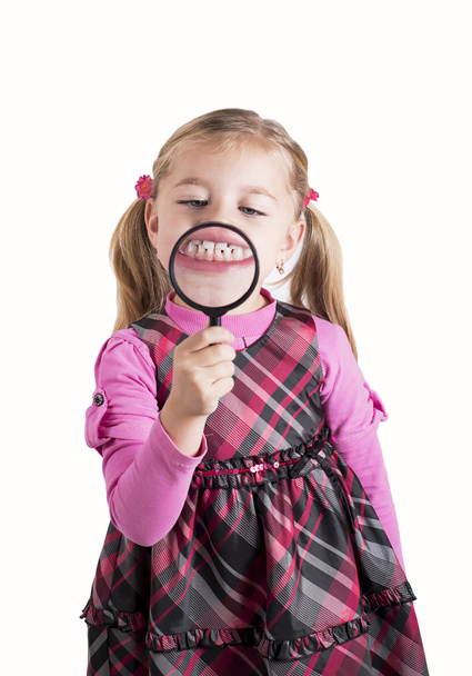 Hauska tyttö näyttää hampaita suurennuslasin läpi
 - Valokuva, kuva