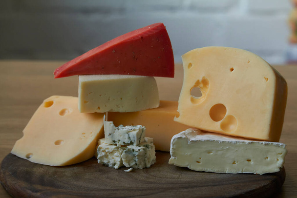 Élelmiszer háttér, különböző típusú sajtok összetétele a fa vágódeszkán, szelektív fókusz - Fotó, kép