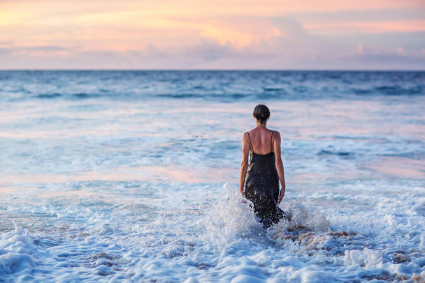 Beautiful woman by the ocean at sunset - Foto, Imagen