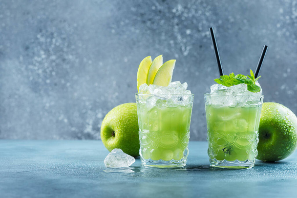 Cóctel verde con hielo y menta. Concepto de bar. mojito de manzana con menta y hielo en el fondo azul, imagen de enfoque selectivo
 - Foto, imagen