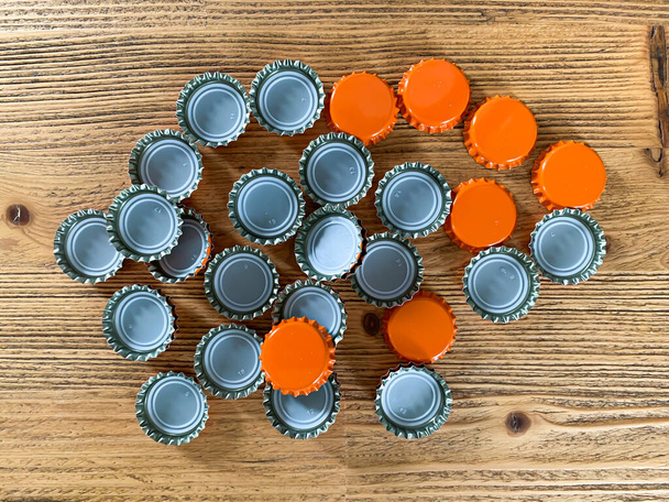 Many orange beer lids, bottle corks tops on a wooden texture top view horizontal image  - Photo, Image