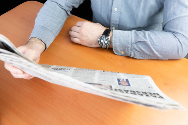 Man reading newspaper on the brown table. - Φωτογραφία, εικόνα