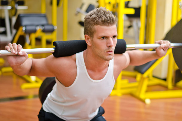 Handsome young man doing squats in gym - Foto, Bild