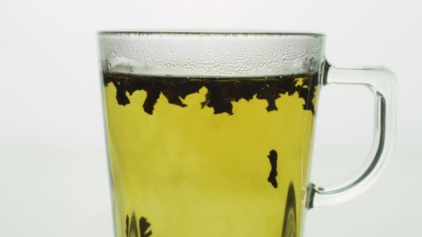 schwarzer Tee Partikel schweben in transparentem Glas Tasse Schaffung Whirlpool, brühen Tee in Nahaufnahme schwarz beleuchtet - Filmmaterial, Video