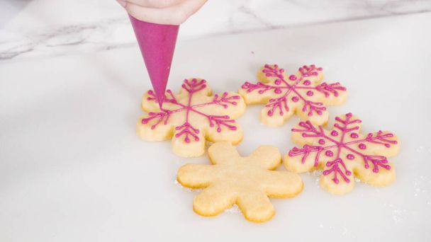 Βήμα-βήμα. Παγωμένη νιφάδα σε σχήμα μπισκότων ζάχαρης με ροζ βασιλικό κερασάκι. - Φωτογραφία, εικόνα
