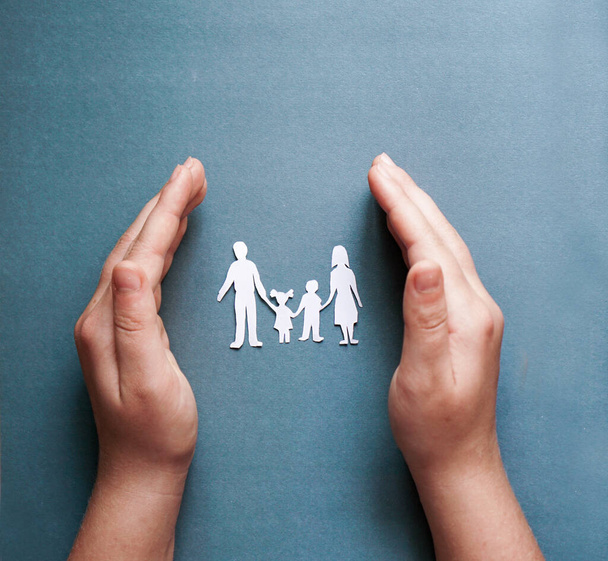 Hände halten Papier Familienausschnitt, soziale Distanzierung Konzept, covid19 auf dem blauen Hintergrund - Foto, Bild