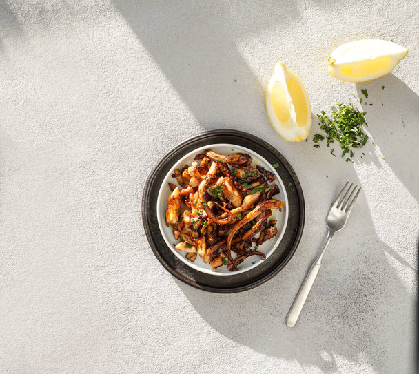 paistettuja mustekalan paloja sitruunalla, pulpo frito, kova suora auringonvalo
 - Valokuva, kuva