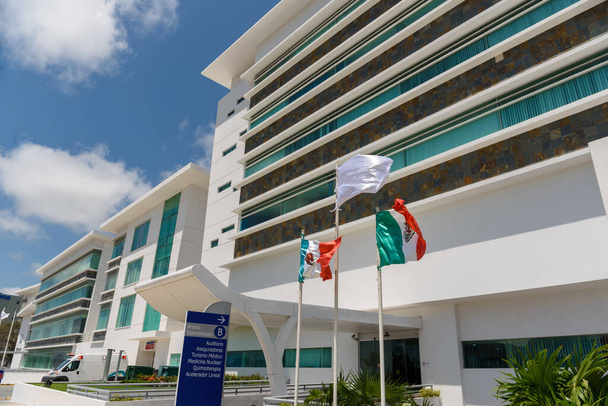 近代的な病院の建物を背景にメキシコ国旗が掲げられている。メキシコ. - 写真・画像