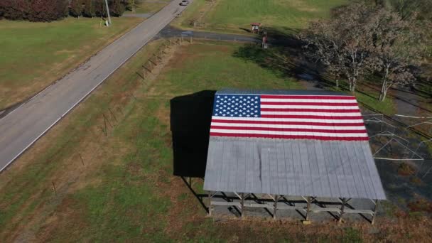 Uma estrada rural com uma bandeira americana pintada em um celeiro perto de uma fazenda nos Estados Unidos - Filmagem, Vídeo