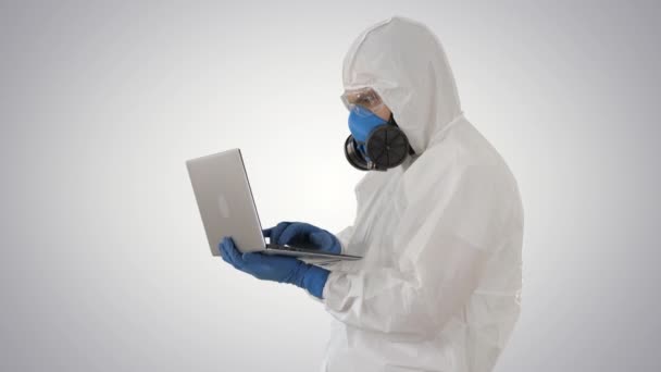Medical doctor in white protective uniform using laptop on gradient background. - Metraje, vídeo