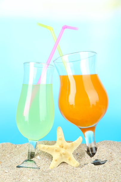 Beach cocktails in sand on blue background - Fotoğraf, Görsel
