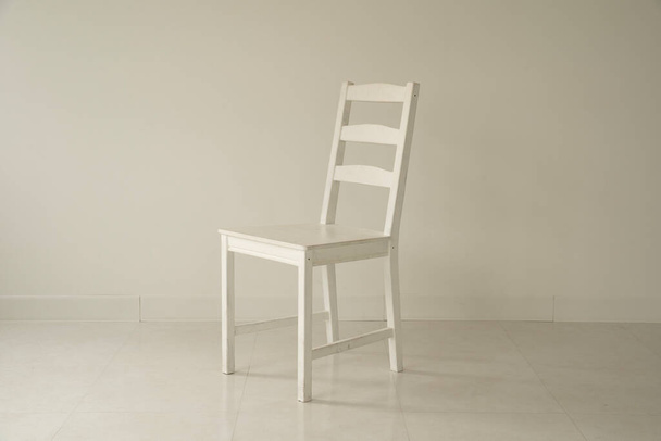 Dentro de una habitación tranquila y blanca con solo sillas de madera blanca
 - Foto, imagen