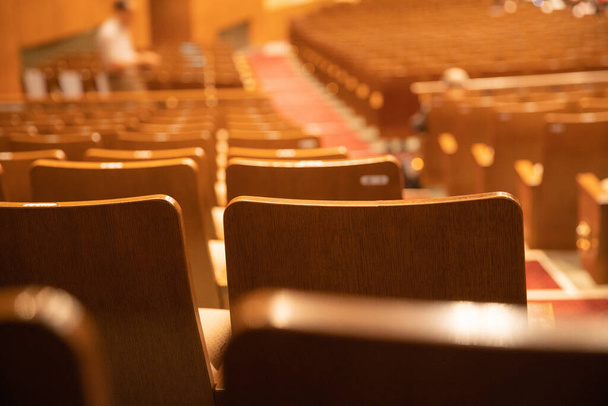 Holzsitze reihen sich in einem leeren Kinosaal aneinander - Foto, Bild