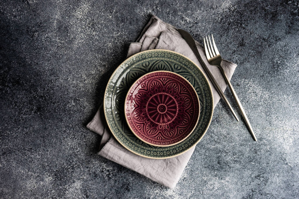 Ρουστίκ ρύθμιση τραπέζι με κεραμικά πιάτα και μαχαιροπήρουνα που σε πέτρινο φόντο με αντίγραφο χώρου - Φωτογραφία, εικόνα