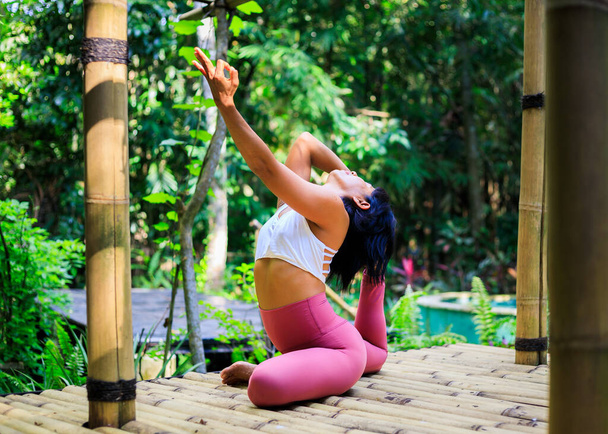 Yoga antrenmanı dışarıda. Asyalı yoga öğretmeni Eka Pada Rajakapotasana, Tek Ayaklı Kral Güvercin Pozu çalışıyor. Göğüs açıcı nefes almakta güçlük çekiyor. Gyan Mudra 'yı teslim edin. Güçlü vücut ve bağışıklık sistemi. Bali - Fotoğraf, Görsel