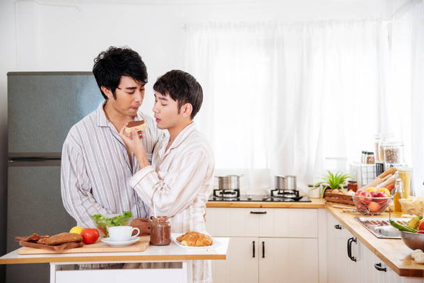 Asian gay couple homosexual cooking together in the kitchen prepare fresh vegetable make organic salad healthy food. Asian people happy time smile, laugh in kitchen. LGBTQ relation lifestyle concept - Photo, Image