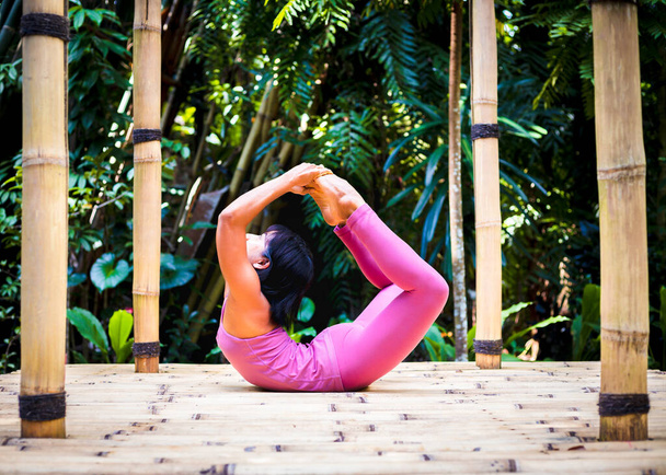 Yoga antrenmanı dışarıda. Asyalı yoga öğretmeni Dhanurasana, Bow Poose çalışıyor. Hatha yogasında Asana 'yı geri bükmek. Esnek omurga. Bağışıklık sistemini destekleyin. Kişisel bakım konsepti. Bali, Endonezya - Fotoğraf, Görsel