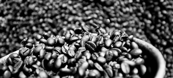 Koffiebonen vers gebraden op zilveren schep, abstracte texturen van gebrande koffiebonen, biologische koffie. Een close-up. Selectieve focus. Volledig frame. - Foto, afbeelding