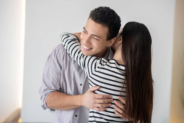 Young smiling dark-haired man hugging a woman. - Fotó, kép
